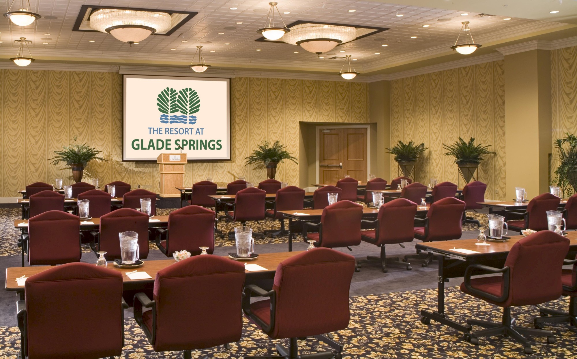 A conference room set up with tables, chairs, and a screen displaying 