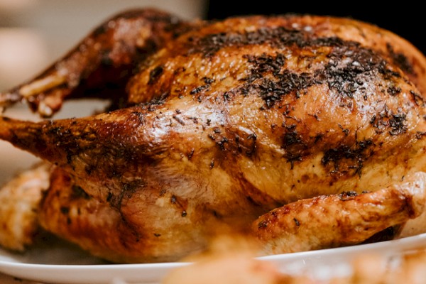 The image shows a roasted chicken garnished with herbs, served on a white plate, ready to be enjoyed.