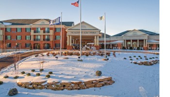 A large brick building with a snow-covered landscape, flags, and a sign that reads 