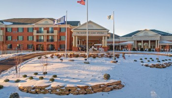 A large brick building with a snow-covered landscape, flags, and a sign that reads 