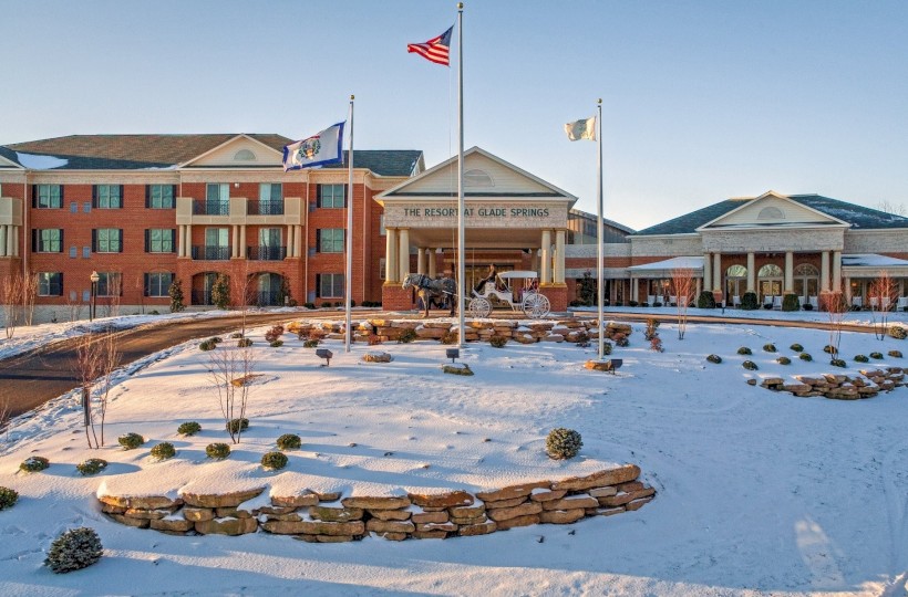 A large brick building with a snow-covered landscape, flags, and a sign that reads 