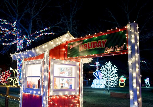 A festive holiday light display with a decorated ticket booth, colorful trees, snowmen, and other light figures creating a cheerful scene.