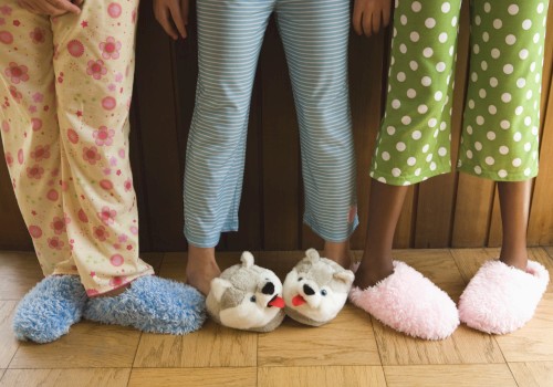 Three people wearing colorful pajamas and fluffy slippers stand on a wooden floor.